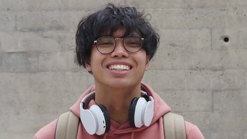 Young Adult Smiling with Headphones and Backpack