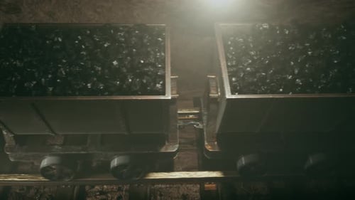 Top of a coal mine wagons slowly moving through narrow underground tunnel.