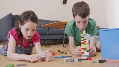 Children Building with Multicolored Blocks on Wooden Floor