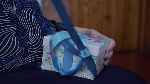 Senior Adult Opens Gift with Blue Ribbon