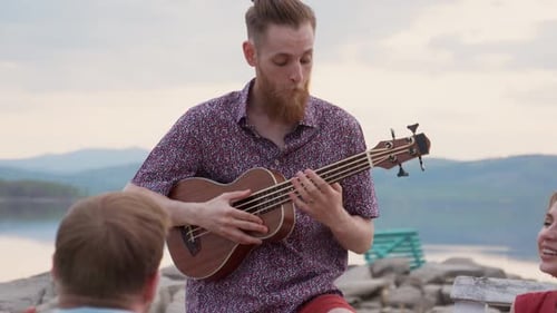Friends Gather by Lake, Man Playing Ukulele