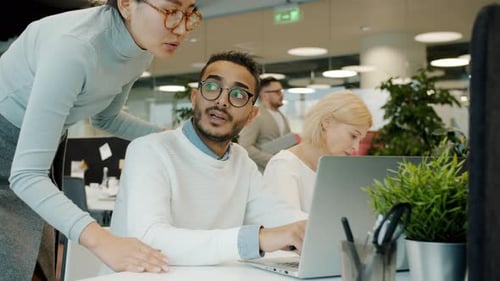 Man and Woman Working with Laptop Talking Sharing Business Ideas in Open Space Office