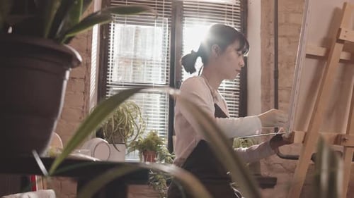 Femme asiatique peignant dans un studio lumineux