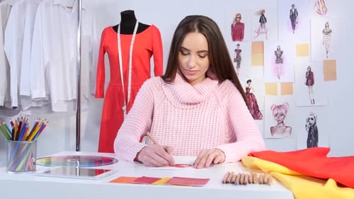 Fashion Designer Drawing Sketches in Studio