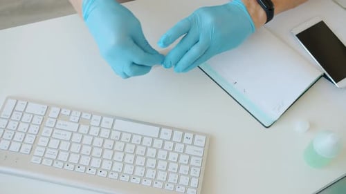 Close-up of Man's Hands in Gloves Wiping Devices with Sanitizer in Workplace During Epidemic