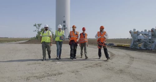 Group of Engineers Walking and Talking on Wind Farm