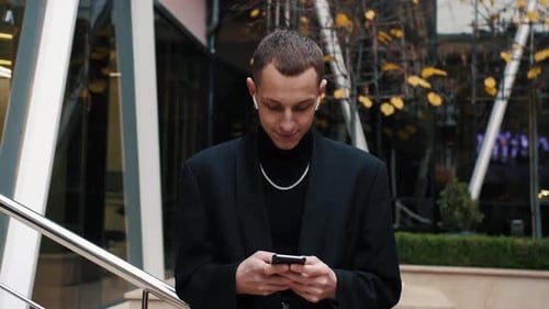 Young Adult Using Mobile Device Outside Urban Building