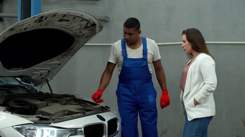 Mechanic Opens the Hood of a Car and Shows the Engine To Woman