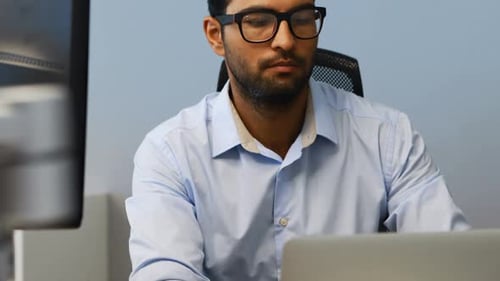 Adult Works At Computer in Office Setting