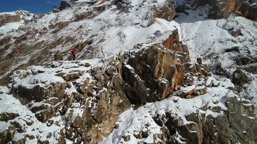 Lone Hiker On Snowy Mountain Peak Aerial View