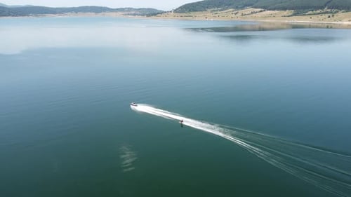 Aerial View of Man Waker Skiing Behind a Boat on Lake at Sunset