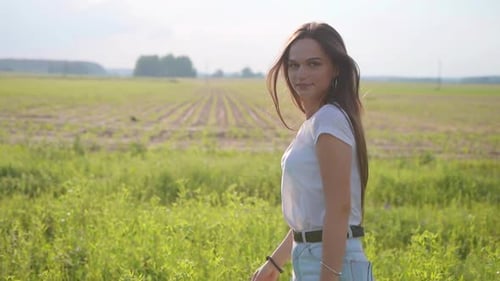 Beautiful Girl with Long Hair Posing in the Meadow on a Summer Day
