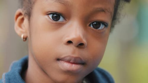 Closeup Pensive Little Girl African American Child Raises Head Looking at Camera Front View Sad Baby