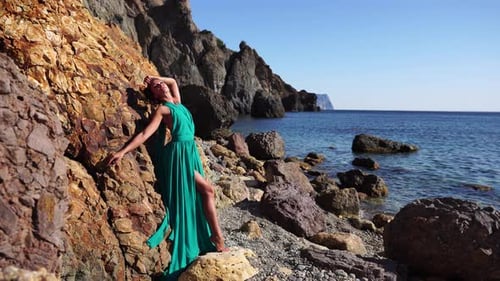 Side View a Young Beautiful Sensual Woman with Black Hair in a Long Mint Dress Posing on a Beach