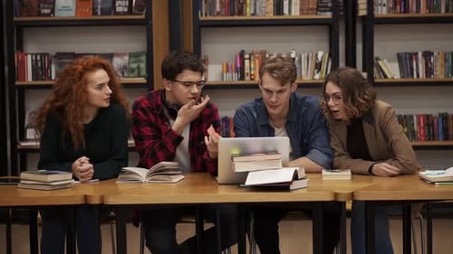 Group of Young Students Talking Using Laptop Explaining Course Work Study Together in Library