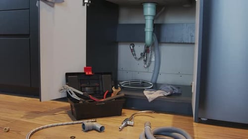 Plumbing Parts Lying before Kitchen Cabinet