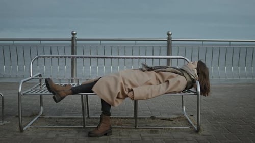 Woman Lies on Bench at the Beach