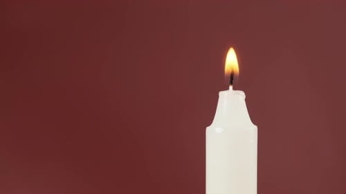 Se enciende una sola vela sobre un fondo rojo. Vela Flame. Lugar para los títulos
