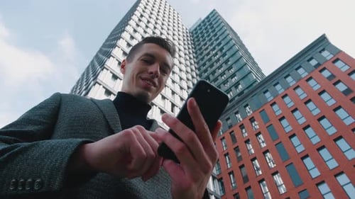 Man Using Business App on Smartphone on City Background. Handsome Young Businessman Communicating on