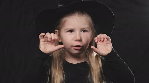 Girl in Witch Costume Gesturing on Black Backdrop