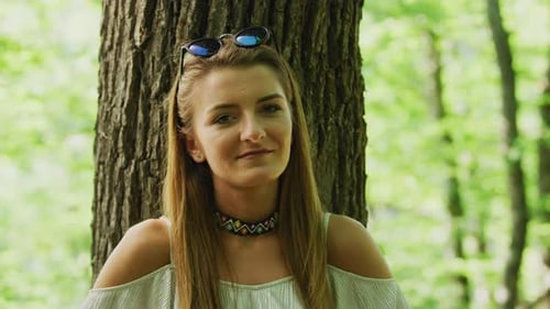 Woman Posing Against Tree in Sunlit Forest