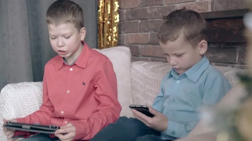Young Boys Use Tablet and Smartphone on Couch
