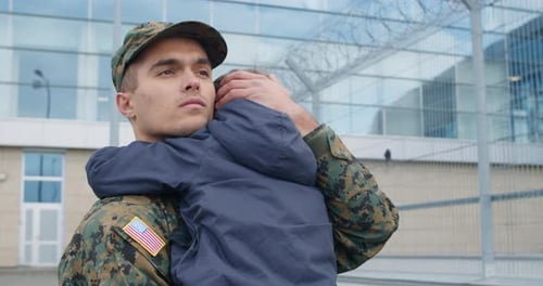 Soldier Hugs Child at Military Building
