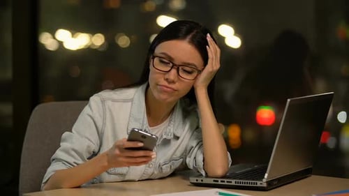 Woman Looks Concerned at Phone, Late Night Office
