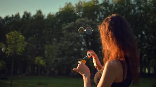 Schöne junge Rothaarige Lady Blow and Burst Seifenblasen im Freien.