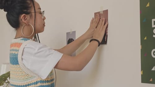 Young Woman Hanging Pictures on Wall at Home