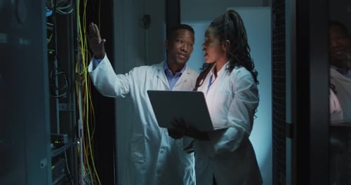 Afroamerikanische Computertechniker arbeiten mit Laptop im Business-Serverraum