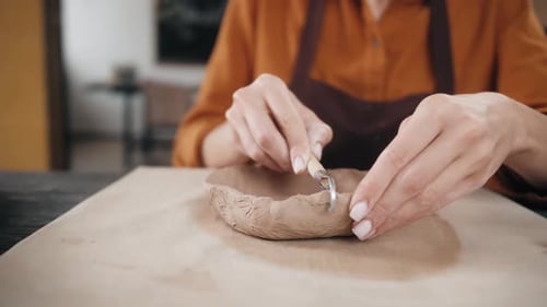 Woman Forming Clay Bowl with Sculpting Tool