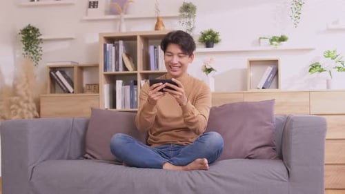 Smiling Young Man Playing Video Game on Phone