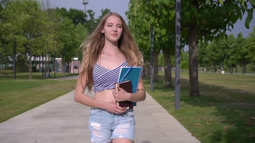 Woman Walking With Books in City Park
