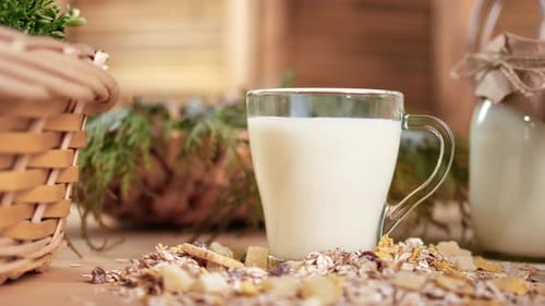 Mesa rústica de madera que sirve Fresh Farm Milk en cristalería y muesli granola en tazón