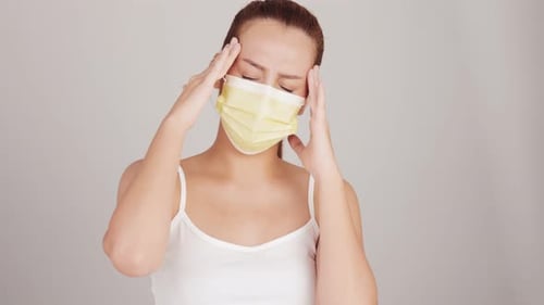 Young Woman with Headache Wearing a Face Mask