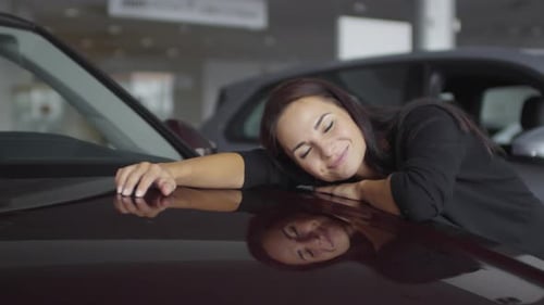 Happy Woman Enjoying Her New Car in Auto Showroom