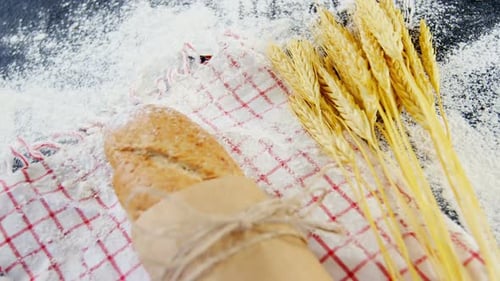 Baguette wrapped in paper, wheat grains and flour