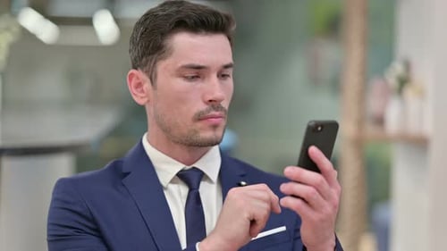 Young Adult Man Using Smartphone in Office Setting