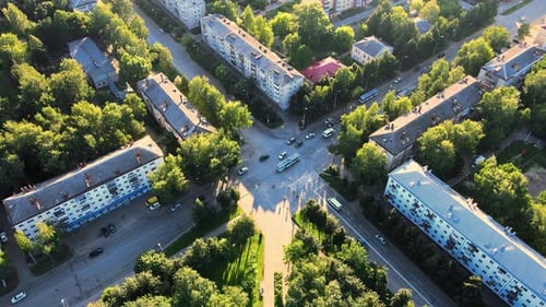 Footage of intersection on sunny evening. Trolleybuses and cars move along road.