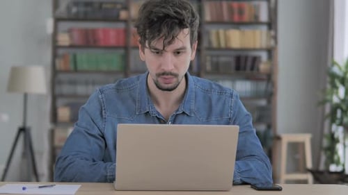 Man Working on Laptop Reacts with Shock