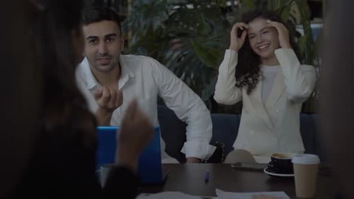 Positive Man and Woman Sitting in Cafe with Coworkers, Talking and Laughing. Group of Positive