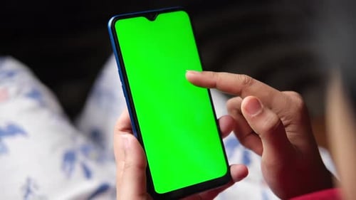 Rear View of Women Hand Holding Smart Phone Sitting on a Sofa