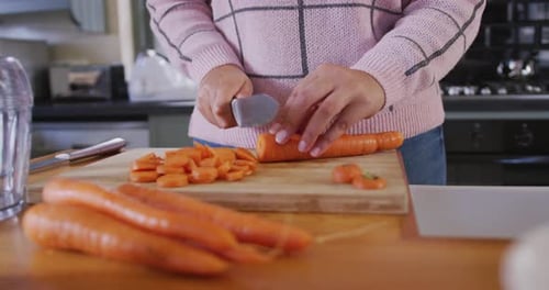 Person Cutting Carrots on a Wooden Board