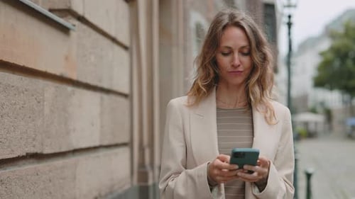 Woman Texting on Smartphone While Walking on City Street