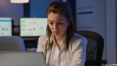 Femme d'affaires travaillant des heures supplémentaires pour respecter la date limite du projet assis dans le bureau d'affaires