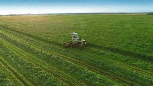 Agricultural Vehicle Cutting Grass in a Green Field