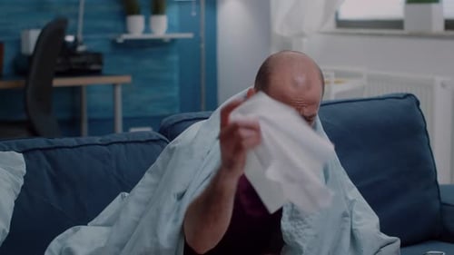 Close Up of Ill Man with Headache Blowing Nose Using Tissues