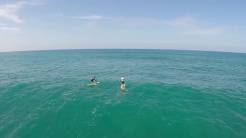 Aerial view of two men sup stand-up paddleboard surfing in Hawaii