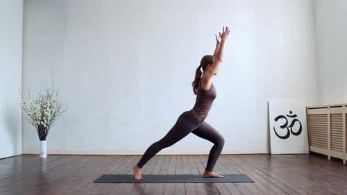 Junge und fitte Frau, die in der Klasse Indoor Yoga praktiziert.